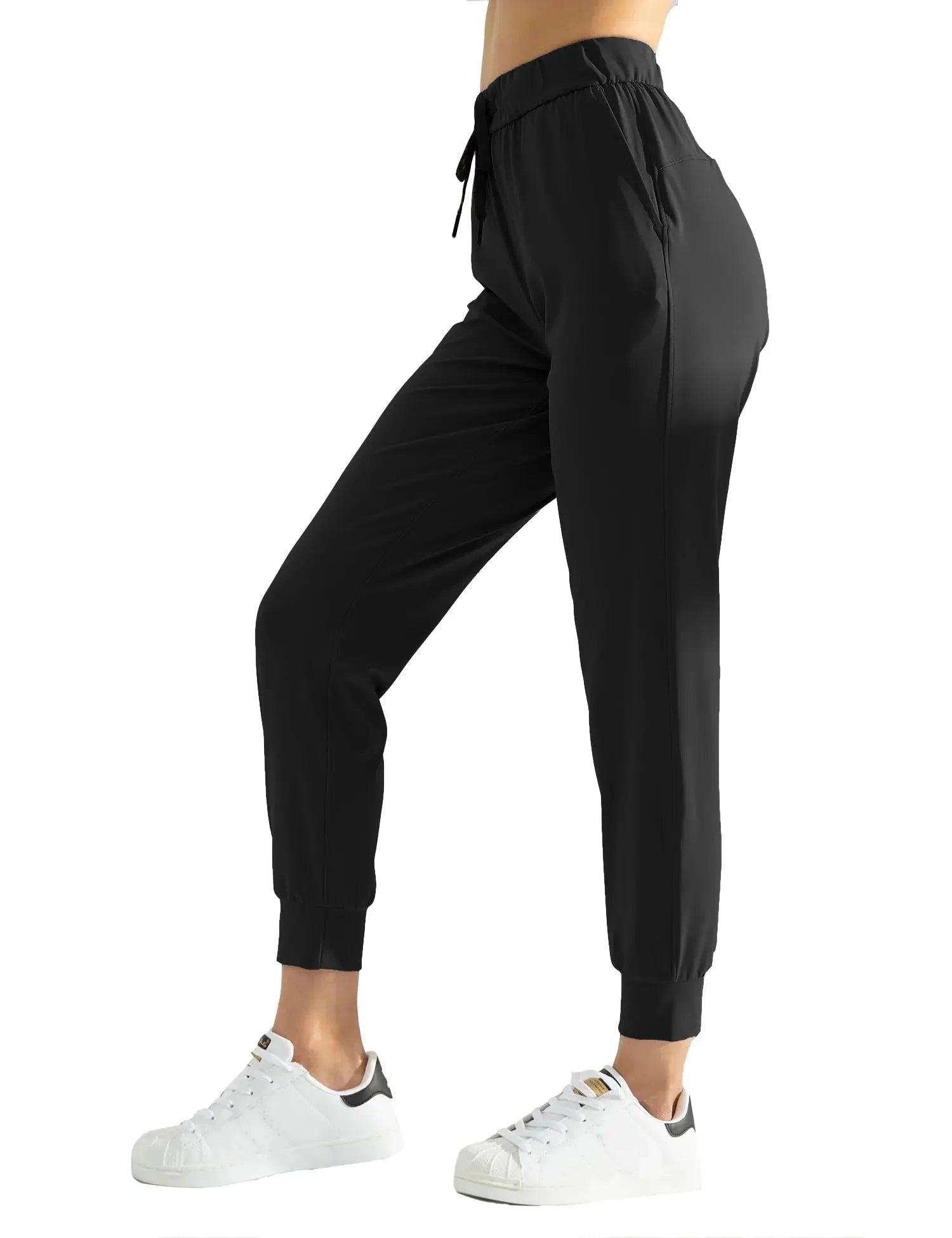 Black women's jogger pants with drawstring waist, elastic cuffs, and side pockets, paired with white sneakers