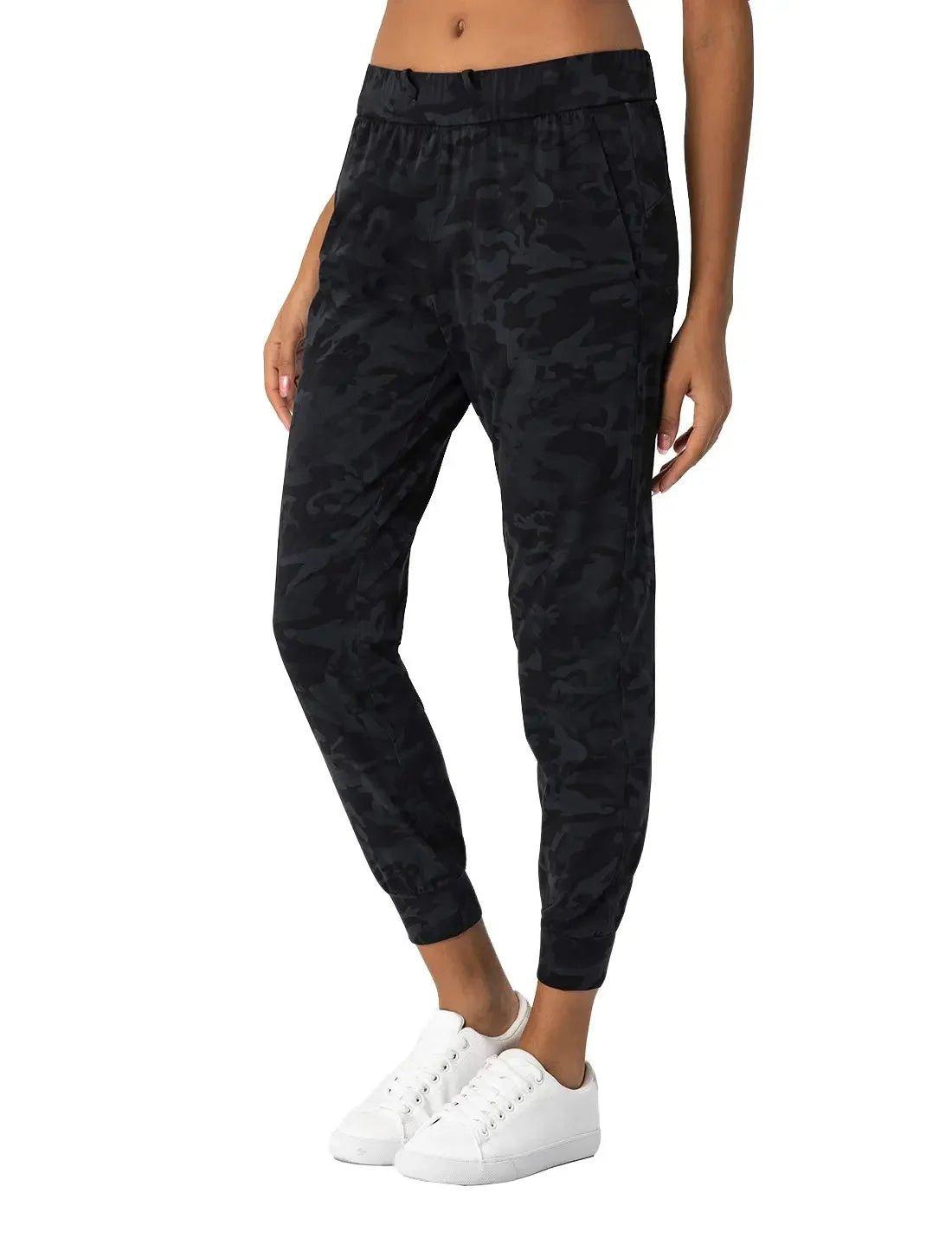 Black camouflage joggers for women, casual athleisure pants with elastic waist and cuffs, paired with white sneakers