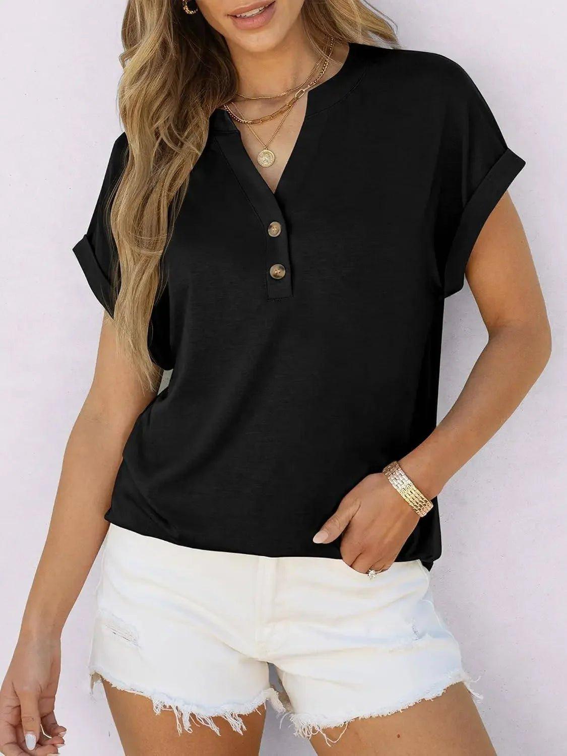 Woman wearing black button-front henley top with rolled sleeves, paired with white denim shorts for casual fashion.