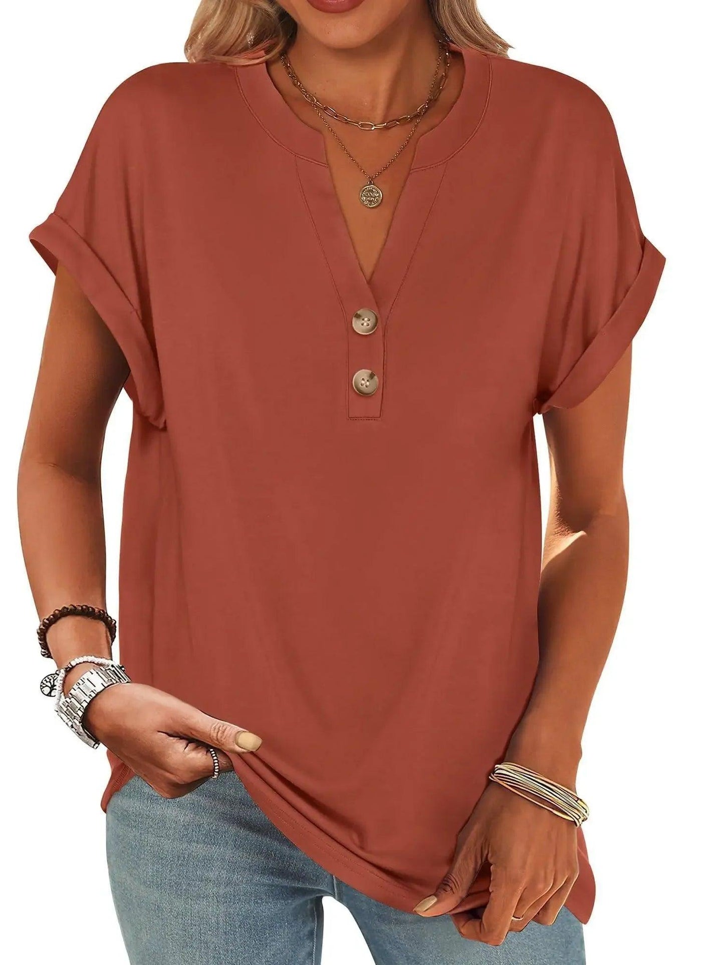 Rust-colored women's V-neck button-up t-shirt with rolled sleeves, paired with jeans and layered necklaces