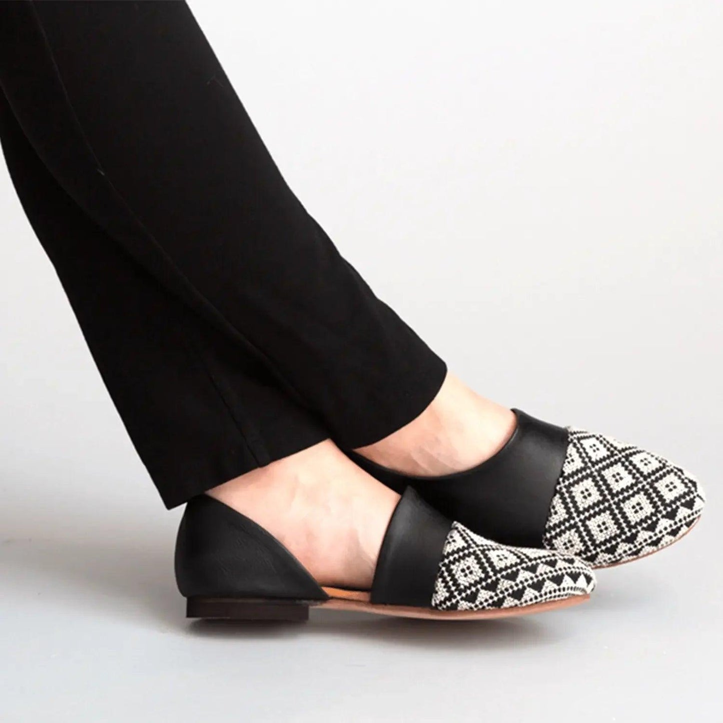 Black and white patterned flats with geometric toe design, worn with black pants for women's fashion