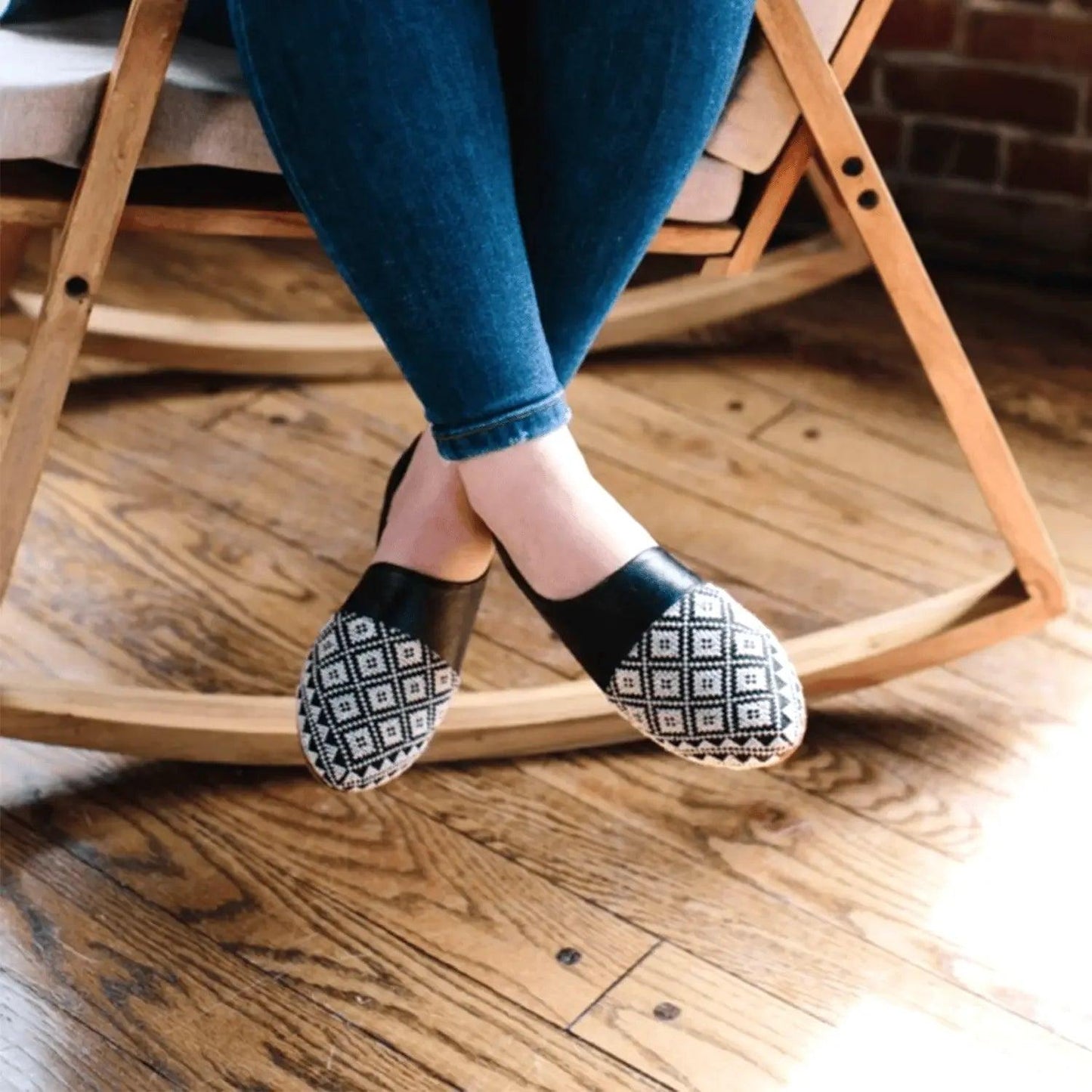Women's black and white patterned slip-on flats with denim jeans, stylish casual footwear