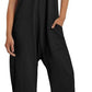 Woman wearing black sleeveless jumpsuit with pockets, white sneakers, and straw hat for summer fashion