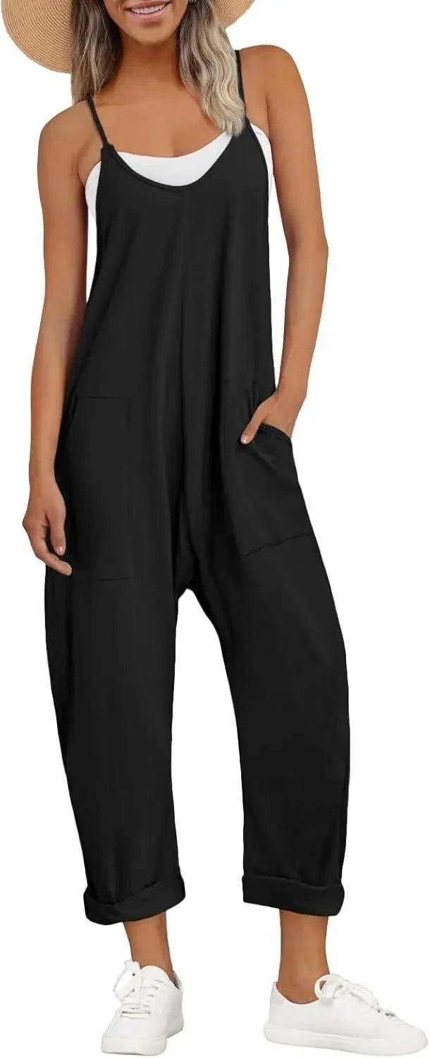 Woman wearing black sleeveless jumpsuit with pockets, white sneakers, and straw hat for summer fashion