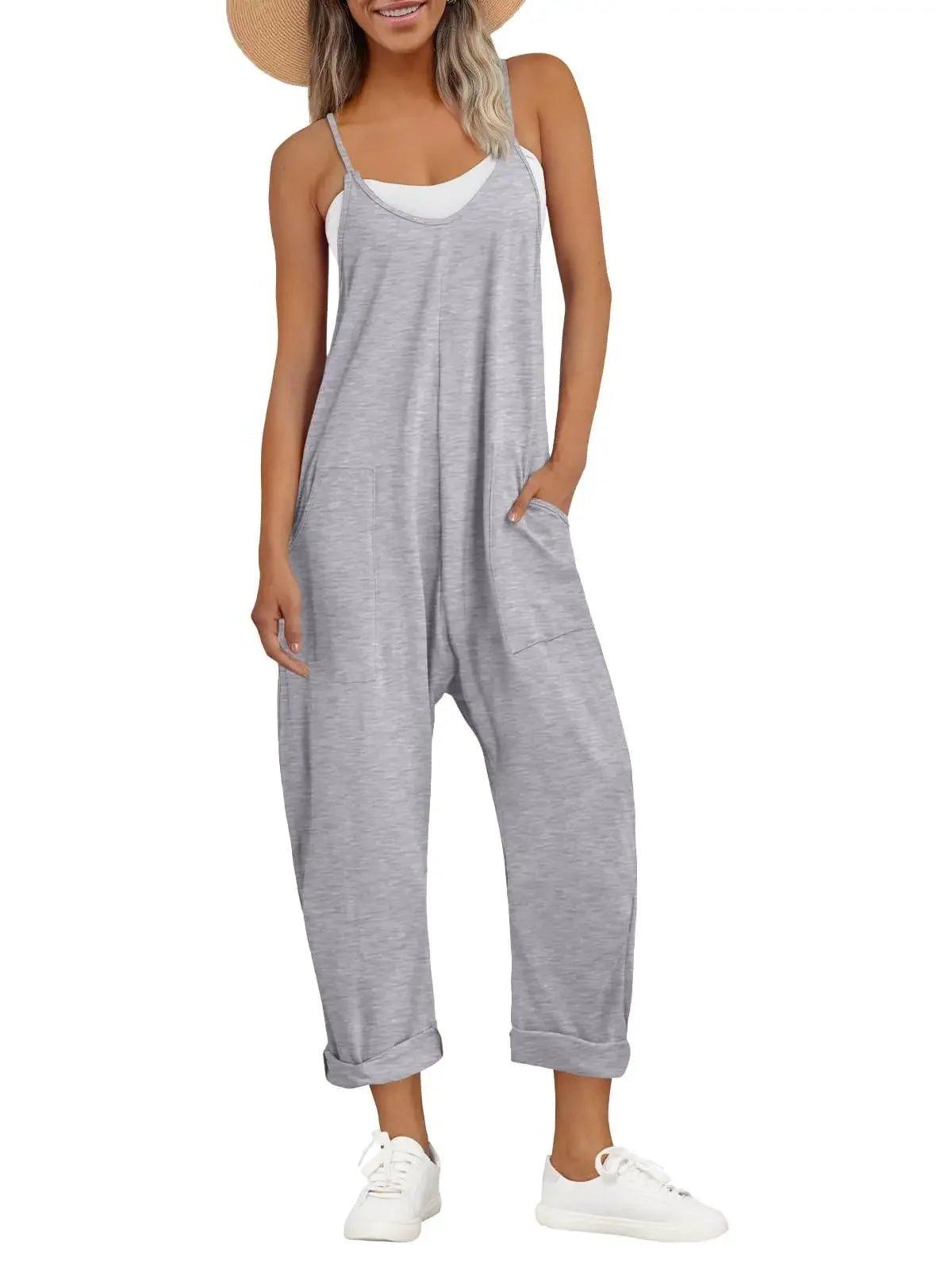 Woman in gray sleeveless jumpsuit with pockets, white sneakers, and straw hat for casual fashion