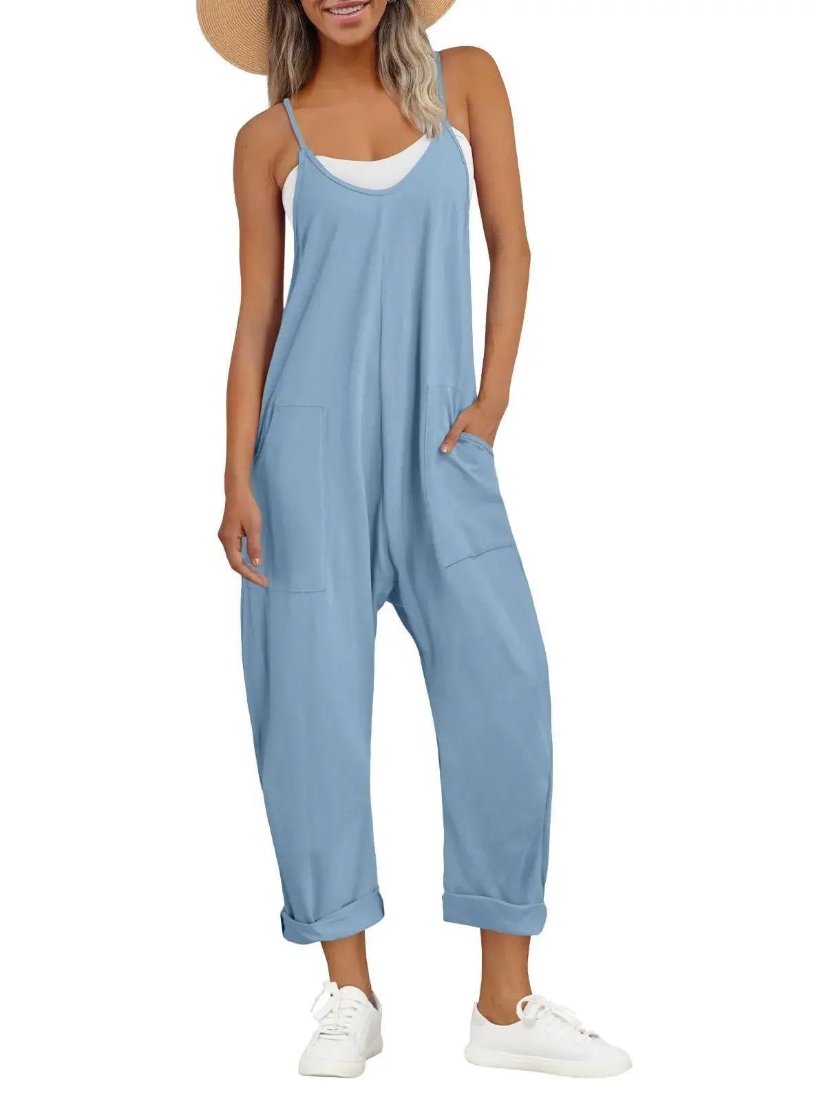 Woman in light blue sleeveless jumpsuit with pockets, straw hat, and white sneakers for casual fashion