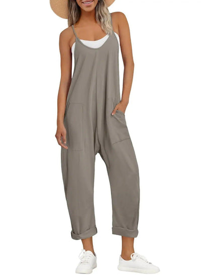 Women's gray sleeveless jumpsuit with pockets, paired with white sneakers and straw hat for casual fashion