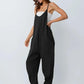 Woman in black sleeveless jumpsuit with wide legs, paired with white top and sandals, fashion outfit