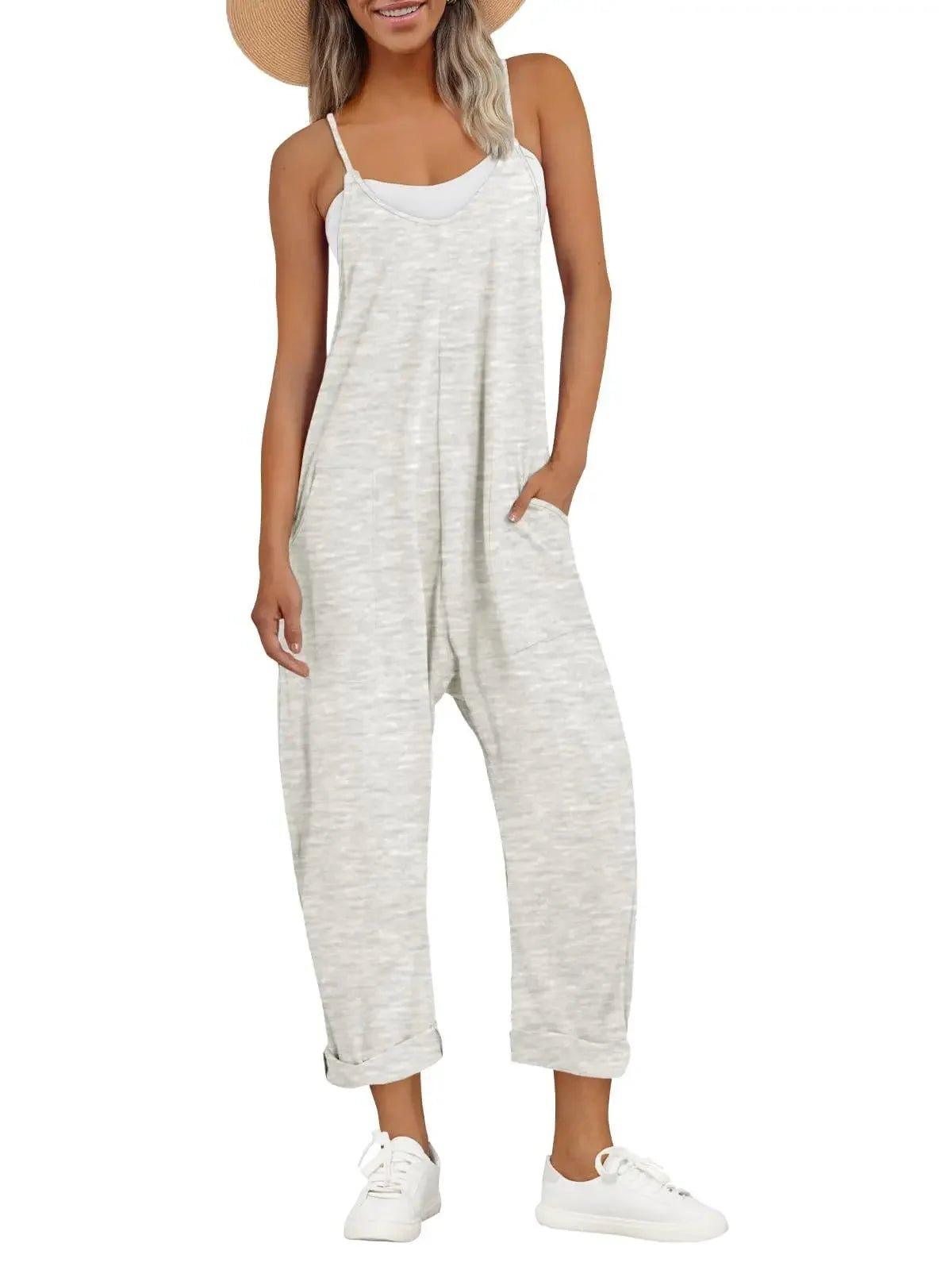 Woman in white textured jumpsuit with thin straps, straw hat, and white sneakers for casual summer fashion