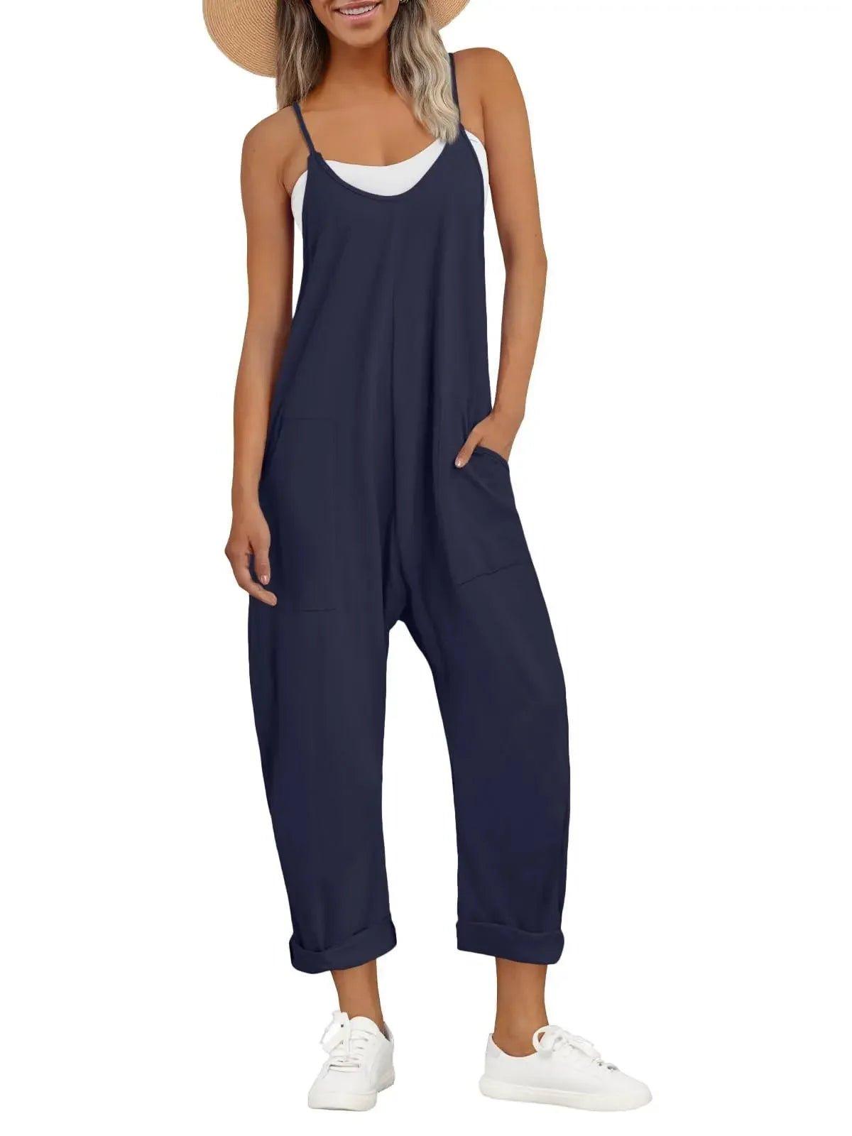 Navy blue women's jumpsuit with pockets, white sneakers, and straw hat for casual summer fashion