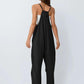 Black women's jumpsuit with thin straps, back view, paired with white top and sandals