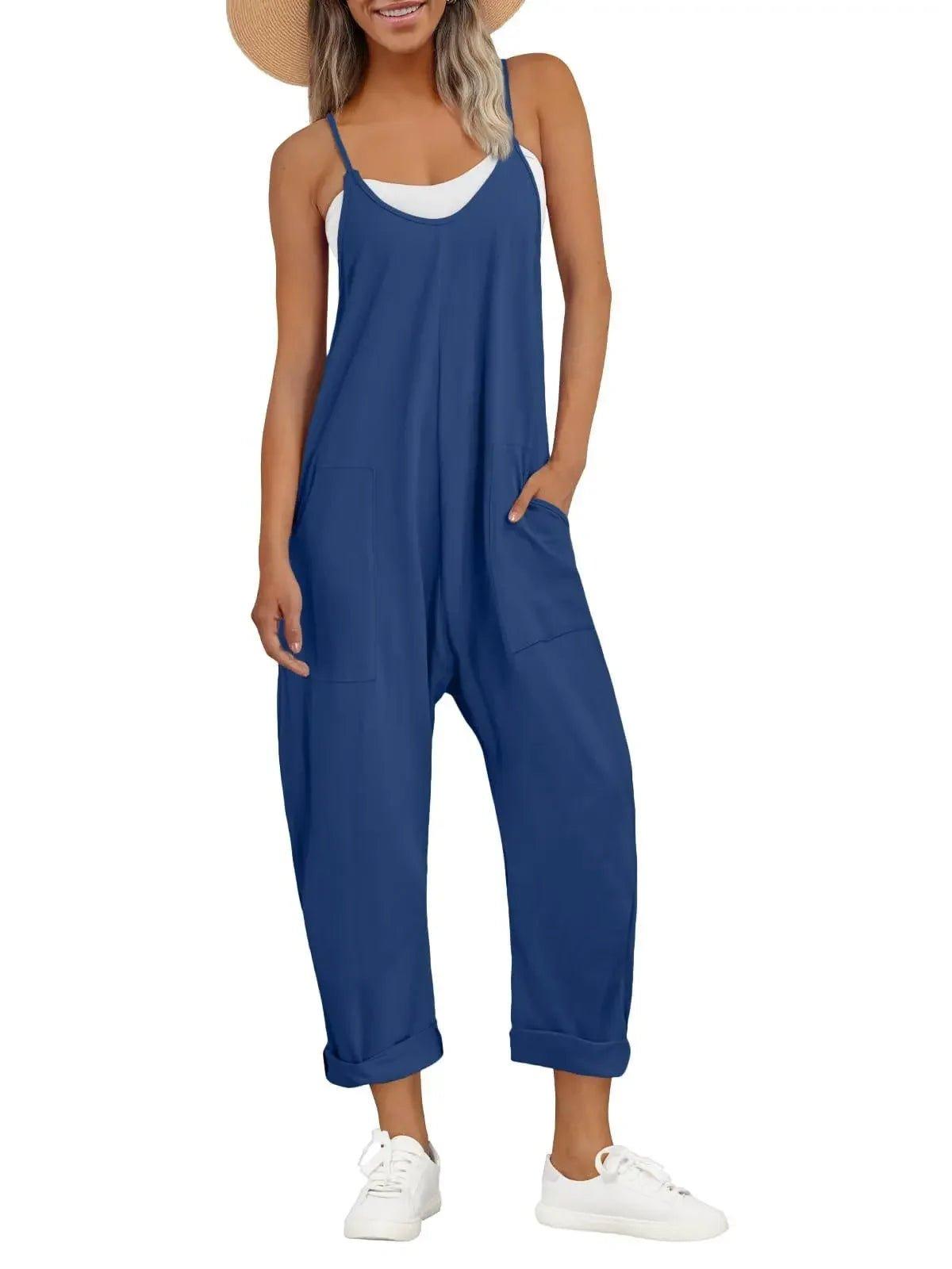 Woman in blue sleeveless jumpsuit with pockets, white sneakers, and straw hat for casual summer fashion