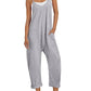 Woman in gray sleeveless jumpsuit with pockets, white sneakers, and straw hat for casual fashion