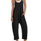 Woman in black sleeveless jumpsuit with pockets, white sneakers, and straw hat for casual summer fashion