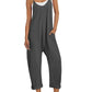 Woman in gray sleeveless jumpsuit with pockets, white sneakers, and straw hat for casual summer fashion