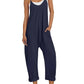 Navy blue women's jumpsuit with pockets, white sneakers, and straw hat for casual fashion