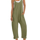 Olive green women's jumpsuit with pockets, paired with white sneakers and a straw hat for casual fashion.
