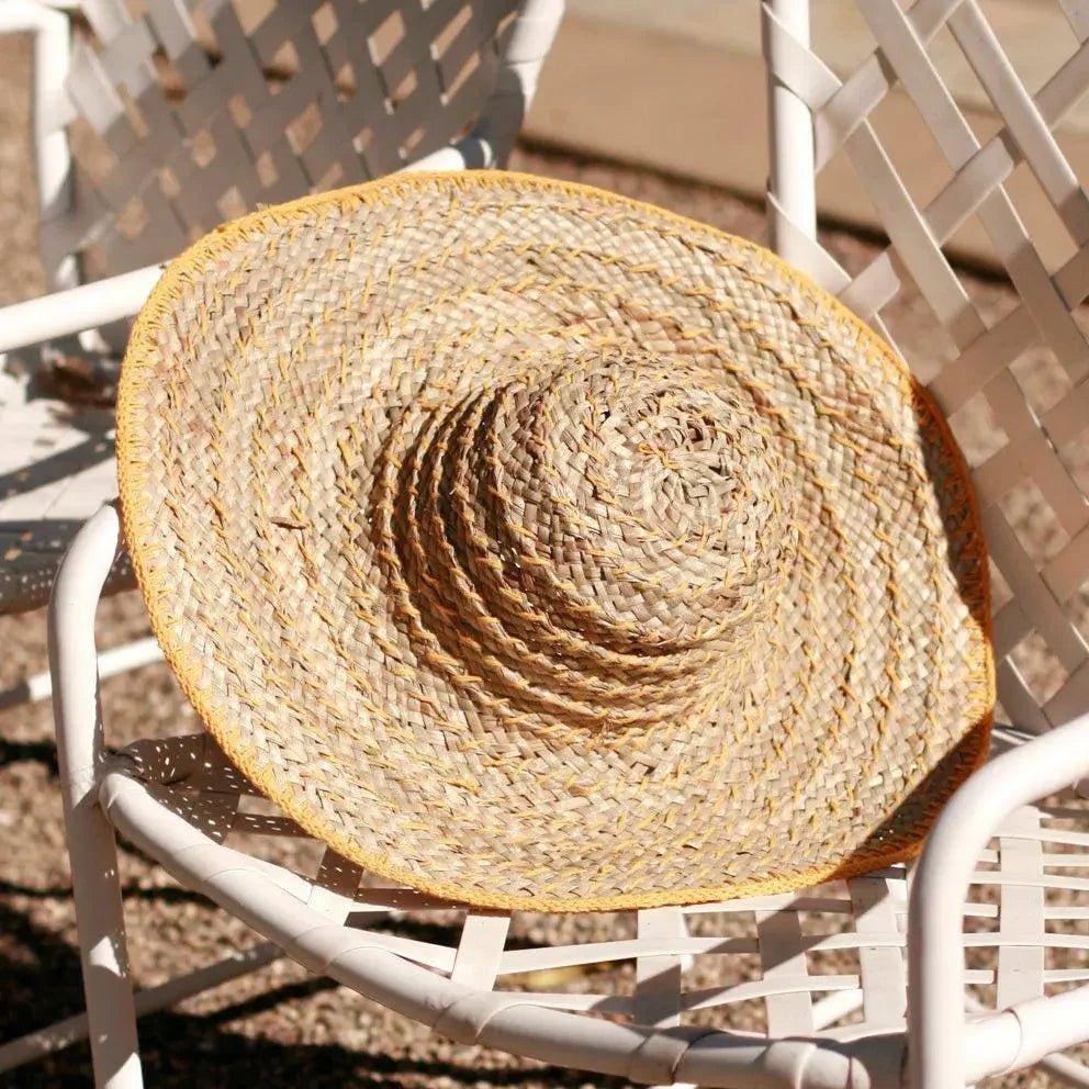 Wide-brimmed straw sun hat with yellow trim, perfect for summer fashion and beach outings.