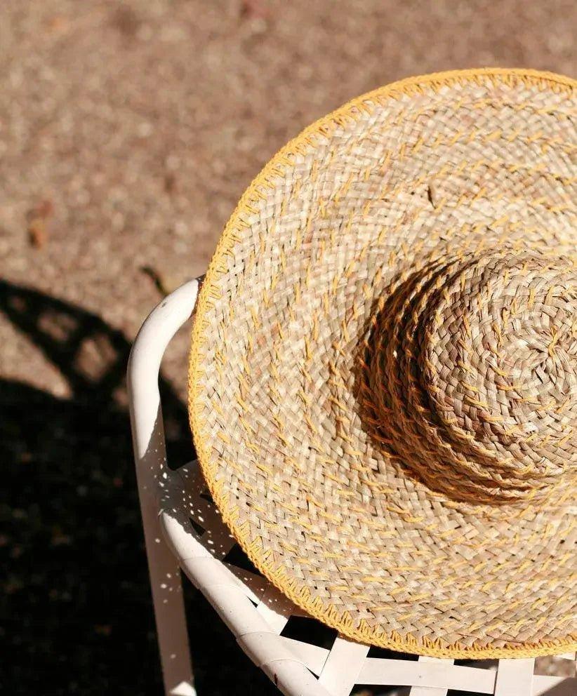 Wide-brimmed straw sun hat with yellow trim, perfect for summer fashion and beach outings