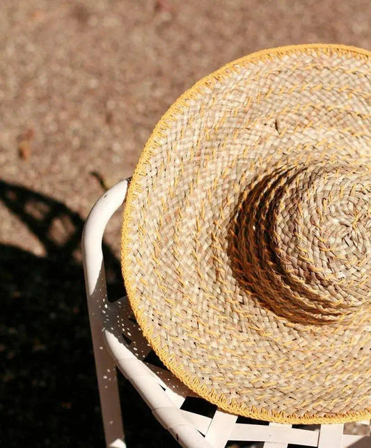Wide-brimmed straw sun hat with yellow trim, perfect for summer fashion and beach outings