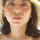 Woman in straw hat with glowing skin, gold hoop earrings, and summer vibes