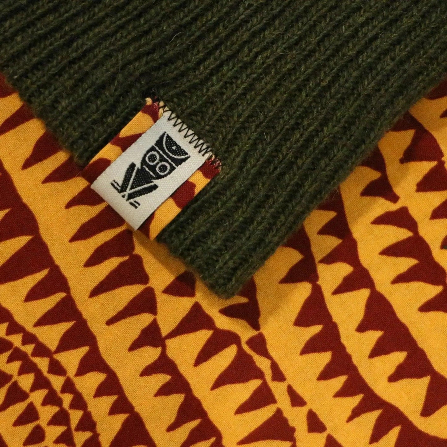 Olive green ribbed knit sleeve with owl tag on geometric print fabric, women's fashion