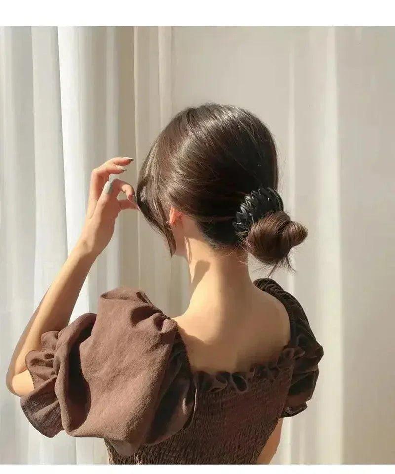 Woman in brown ruffle top with sleek bun hairstyle, elegant fashion look