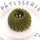 Olive green velvet hair scrunchie on white plate with PÂTISSERIE text, women's fashion accessory