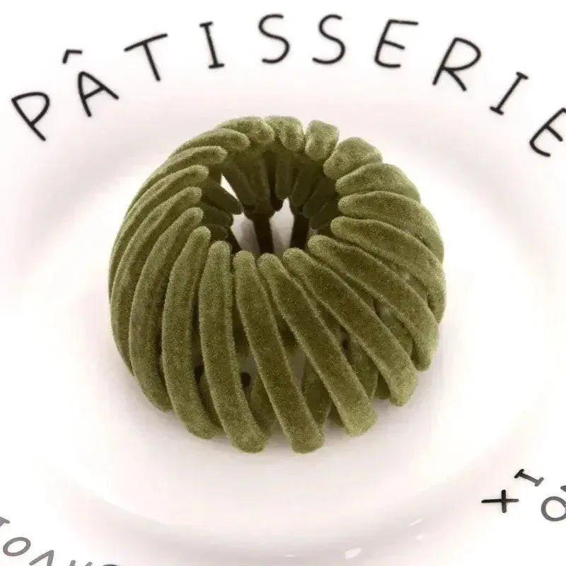 Olive green velvet hair scrunchie on white plate with PÂTISSERIE text, women's fashion accessory
