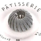 Gray velvet hair scrunchie on white plate with Pâtisserie text, women's fashion accessory