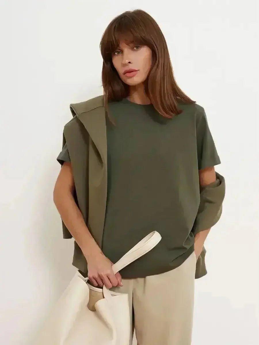 Woman in olive green oversized top with ruffled sleeves, beige pants, and white tote bag