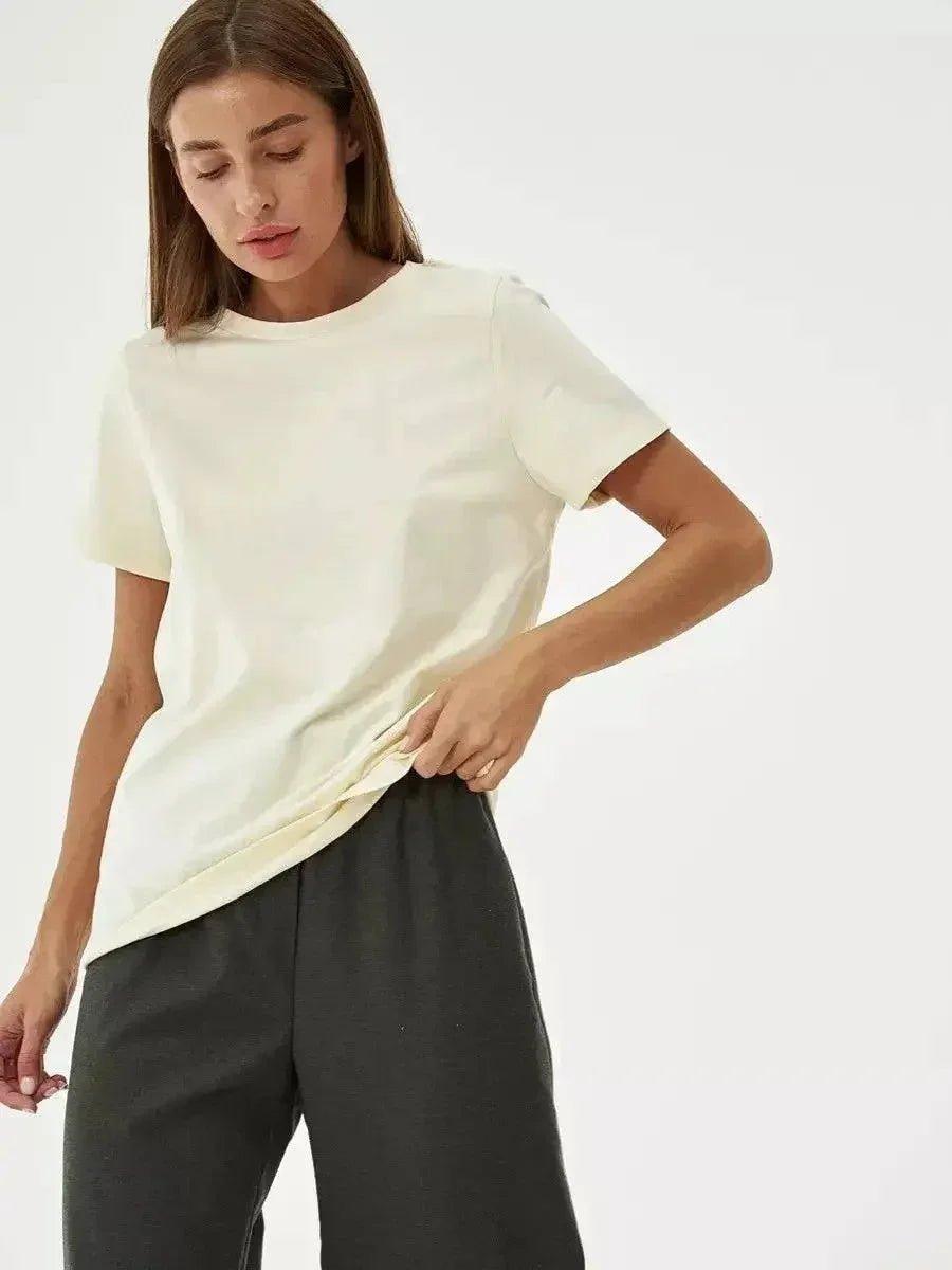Woman modeling cream basic t-shirt with relaxed fit, paired with black pants for casual fashion look