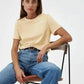 Woman in beige t-shirt and blue jeans sitting on chair, casual fashion outfit