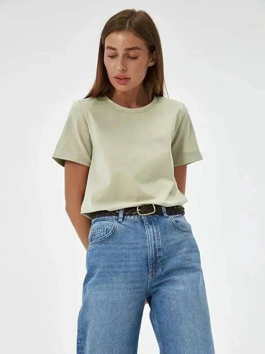 Woman wearing mint green t-shirt and high-waisted blue jeans, casual fashion outfit