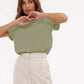 Woman in green short sleeve top and white high-waist pants, stylish casual fashion outfit