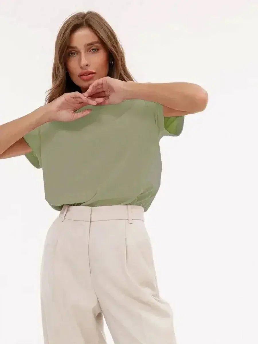 Woman in green short sleeve top and white high-waist pants, stylish casual fashion outfit