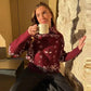 Woman in maroon bandana print sweater holding coffee mug, cozy indoor fashion look