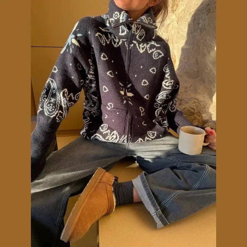 Woman wearing cozy bandana print zip-up sweater with jeans and boots, holding coffee mug