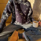 Woman wearing cozy bandana print zip-up sweater with jeans and tan boots, holding coffee mug