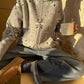 Woman in cozy patterned zip-up sweater, wide-leg jeans, and brown boots holding coffee mug