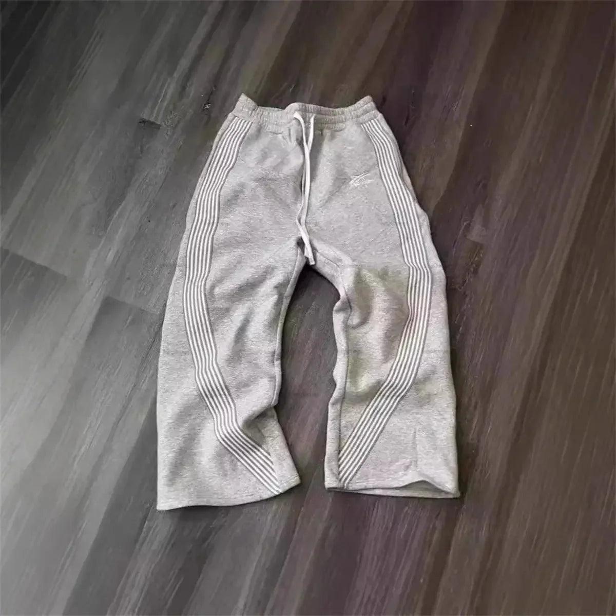 Gray women's sweatpants with side stripes, casual lounge wear on wood floor
