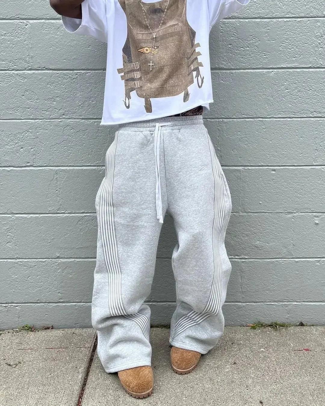 Gray wide-leg sweatpants with side stripes, paired with graphic tee and brown boots, streetwear fashion