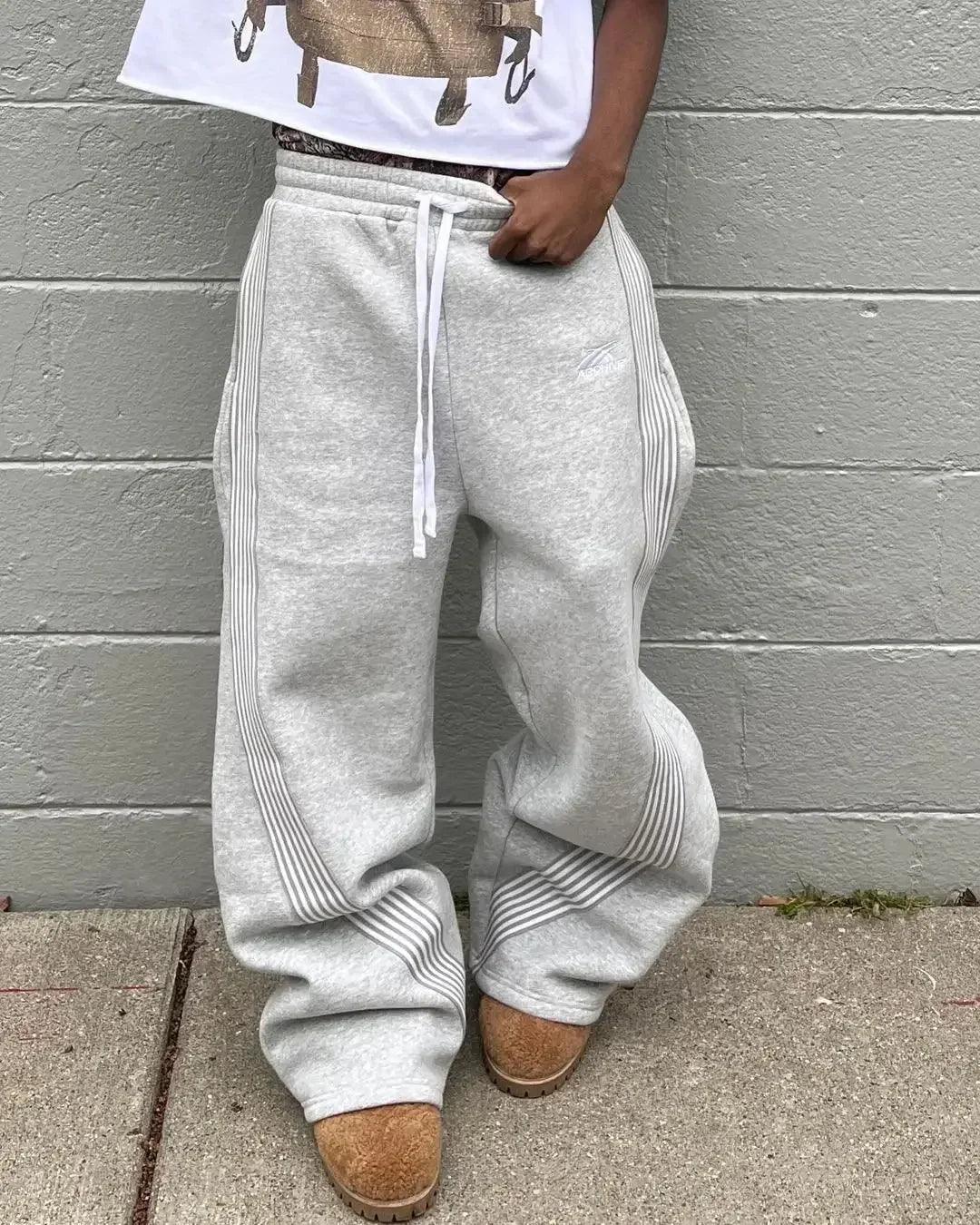Gray wide-leg sweatpants with side stripes, drawstring waist, paired with cozy slippers for casual women's fashion
