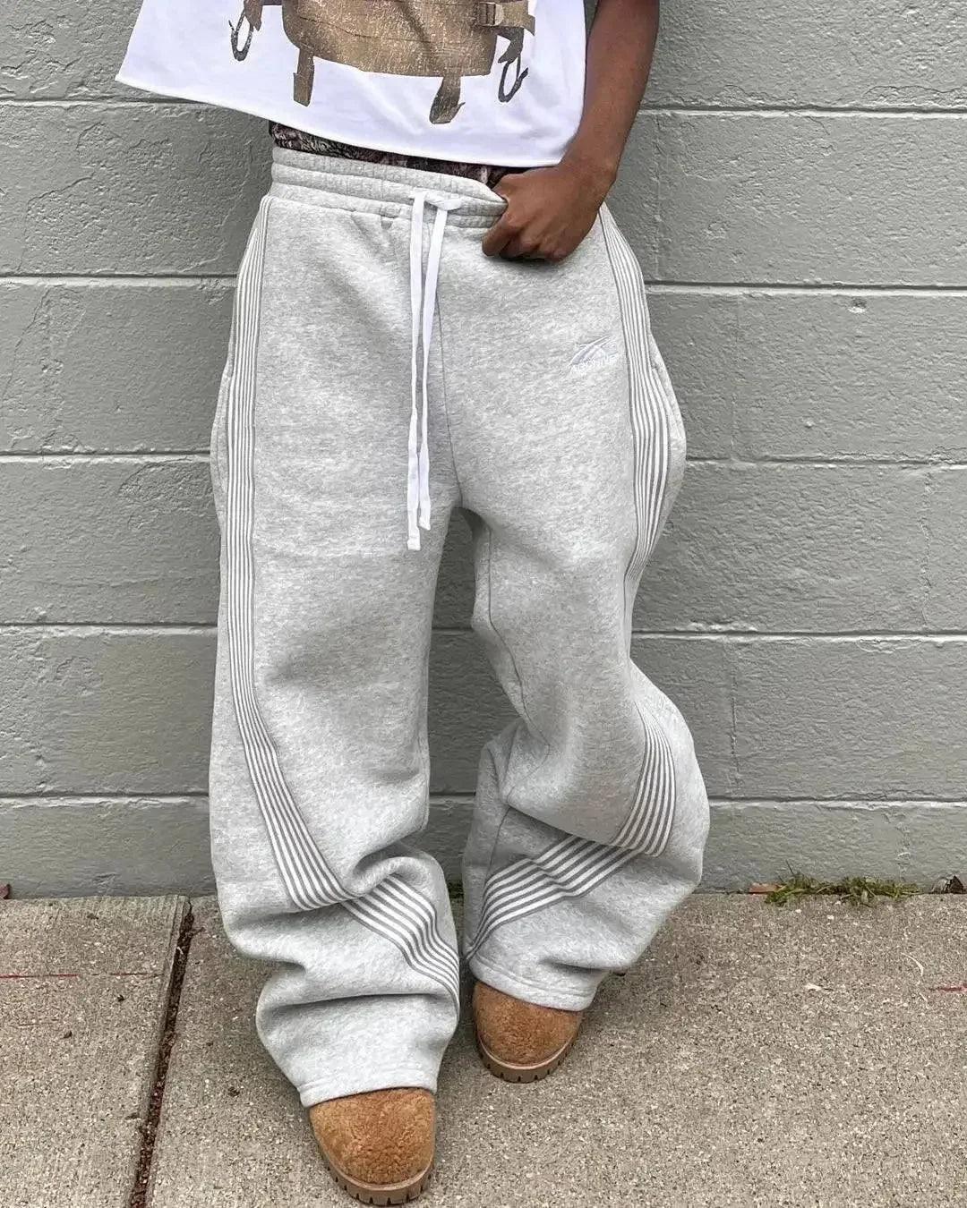 Gray wide-leg sweatpants with side stripes, drawstring waist, paired with cozy slippers for casual fashion