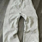 Gray women's sweatpants with white side stripes, drawstring waist, laid on wood floor