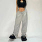 Woman in black crop top and gray drawstring sweatpants with fuzzy black sandals, fashion outfit