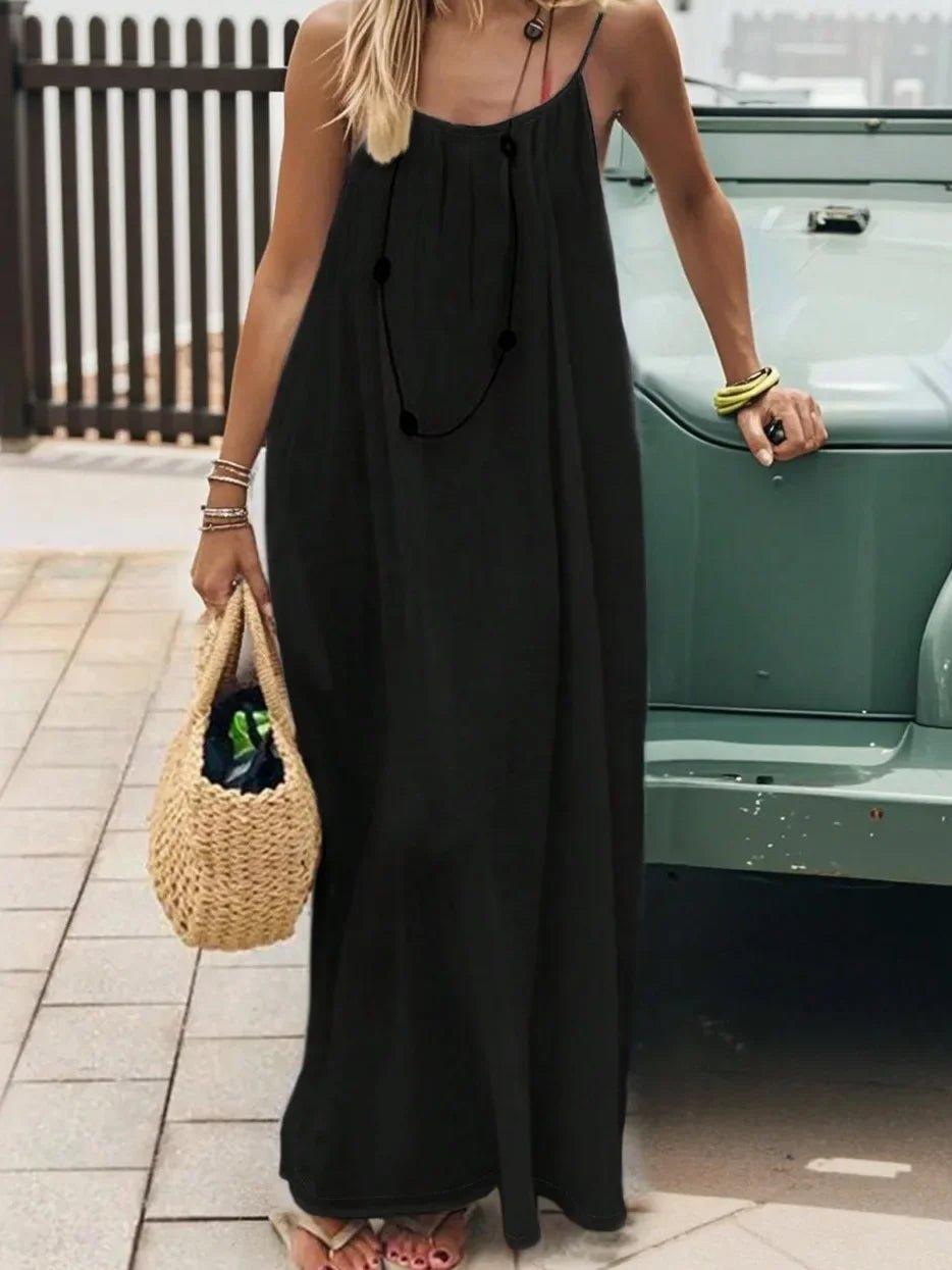 Woman in black spaghetti strap maxi dress with straw bag, summer fashion outfit