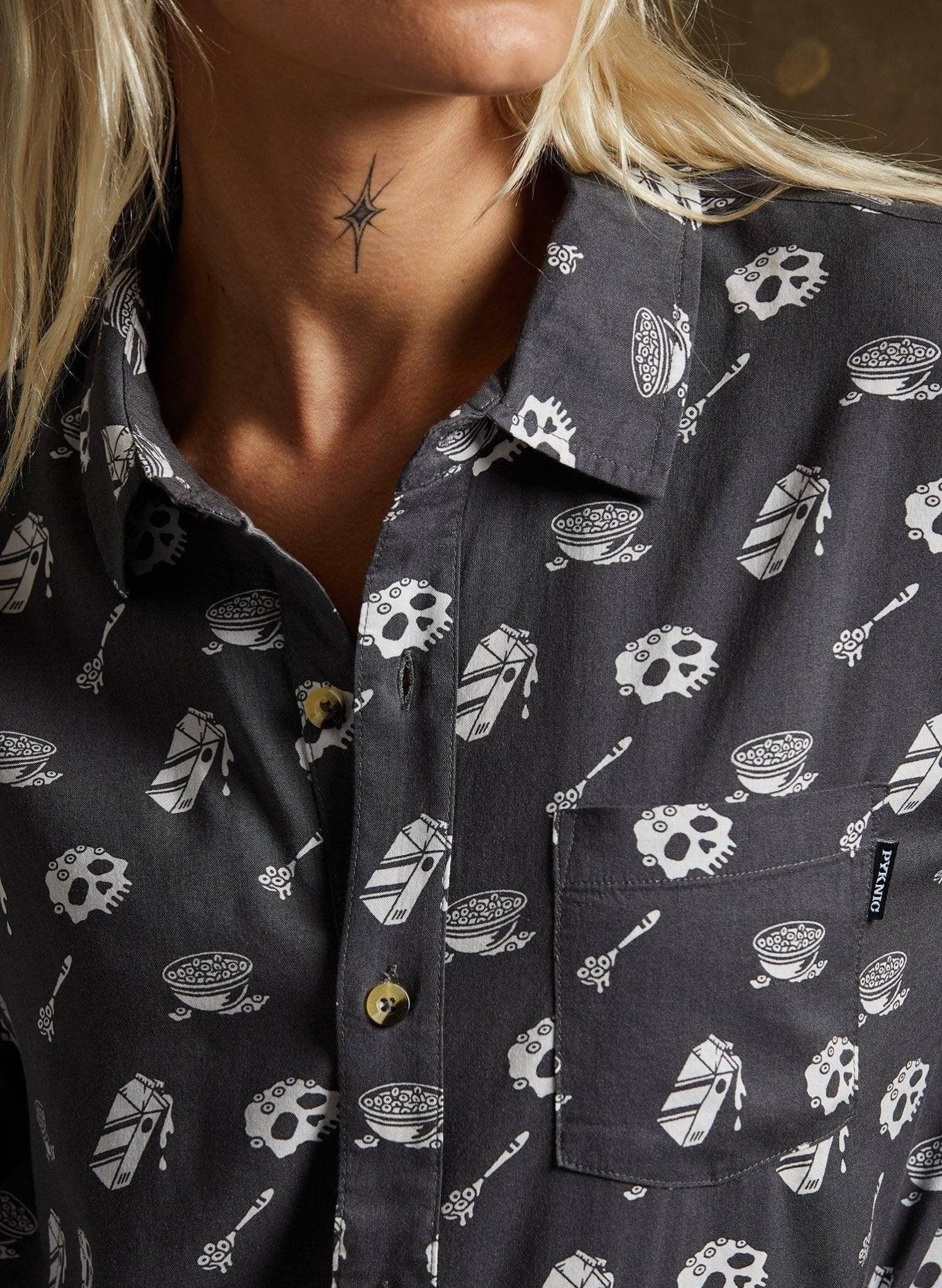 Woman wearing dark button-up shirt with skull and cereal bowl print, fashion top