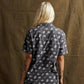 Woman wearing dark short-sleeve shirt with white skull and bone print, back view, fashion style