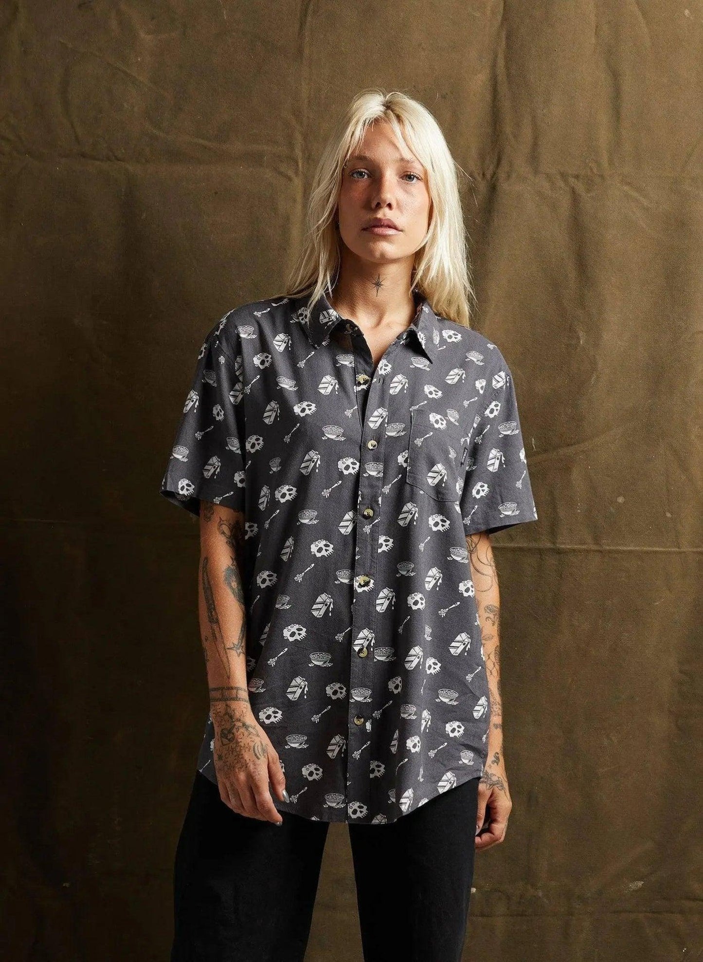 Woman wearing edgy skull print short sleeve button up shirt, fashion top for women